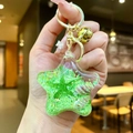 Green star-shaped acrylic ocean quicksand keychain with seashells and gold bell - Green Star With Golden Hardware