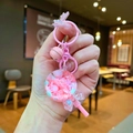 Pink lollipop keychain with colorful beads, liquid oil, and bow charm held in hand - Pink