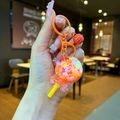 Détail d'un porte-clés sucette orange avec sequins flocons et petite clochette rouge - Orange