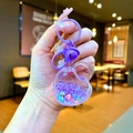 Nahaufnahme des lila herzförmigen Glitzerschlüsselanhängers mit kleinen Blumen und Sternen - Karabiner-Stil / Lila