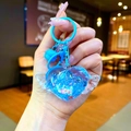 Detail of blue heart keychain with liquid glitter, small wings, and a matching bell charm - Lobster Clasp Style / Blue