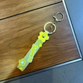 Macro detail of translucent green Sakura silicone strap keychain with gold lobster clasp - Yellow
