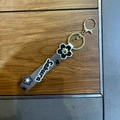 Close-up of Sakura silicone strap keychain with gold lobster clasp and floral charms - Black
