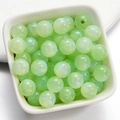 Dettaglio macro di perline tonde in resina verde chiaro aurora con effetto shimmer - Verde