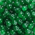 Nahaufnahme dunkelgrüner, lichtdurchlässiger Glasperlen für DIY-Schmuck mit Glanzeffekt - 6mm / 50 Stück / Smaragdgrün