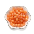 Makro-Detail von orangefarbenen Harzperlen mit Wolkenmarmorierung in einer Keramikschale - Orange