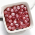 Macro detail of round pink cat eye resin beads in a white ceramic tray for DIY jewelry - 8mm / Deep Pink