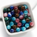 Detailed view of colorful resin cat-eye beads in a white tray for DIY jewelry making - 8mm / Random Mixed Colors