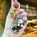 Detail of candy-shaped acrylic keychain with cartoon panda and golden bell pendant - Gold Hardware Round Candy Black Gold Milk Bottle Panda