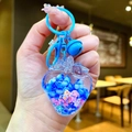 Detail eines blauen Erdbeeren-Schlüsselanhängers mit Perlen und bunten Blumen im Inneren - Blau