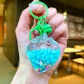 Close-up of strawberry shaker keychain with blue beads, star sequins and green bell - Green