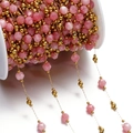 Detail of pink faceted natural stone beads and gold spacers on a white spool roll - Gold Style 09