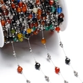 Detailed close-up of colorful faceted stone beads and silver metal chain on a white spool - Steel Color Style 01