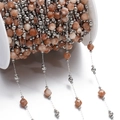 Macro shot of faceted orange natural stone beads and silver metal beads on a spool - Steel Style 03