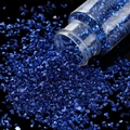 Makroaufnahme von königsblauen Glassteinen, die aus einer klaren Flasche herausströmen - 30ml Flasche / Blau