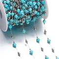 Close-up of turquoise faceted stone beads and silver metal beads on a white spool - Steel Style 06