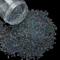 Macro detail of mixed size iridescent glass bubble beads pouring for DIY nail art - 28g per Box / Grey Green