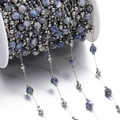 Macro shot of blue faceted natural stone beads and silver metal chain on a white spool - Steel Style 10