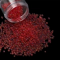 Detailed macro shot of red iridescent glass bubble beads pouring from a transparent jar - 28g per Box / Red