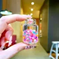 Detailed close-up of a mini acrylic storage jar with colorful beads and flower charms - Gas Tank Shape