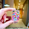Détail d'un porte-clés mini bouteille avec perles colorées et paillettes liquides - Design de canette de cola