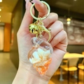 Detail of seashell resin keychain with internal natural shells and golden bell accessory - Conch Pendant (Gold Buckle) / Orange