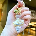 Detail of seashell keychain with mini shells, blue sequins, and golden bell charm - Conch Pendant (Gold Buckle) / White