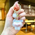 Macro detail of iridescent mini Lilith acrylic keychain with gold clasp and pink accents - White