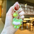 Detail of a green cartoon character keychain with acrylic bubble bead and gold metal clasp - Green