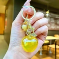 Detail view of a yellow translucent apple keychain with gold leaf and rhinestone accents - Gold Hardware Electroplated Apple / Aurora Yellow