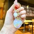 Macro detail of iridescent apple-shaped resin keychain with sparkling gold leaf charm - Gold Hardware Electroplated Apple / Iridescent White