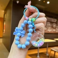 Nahaufnahme vom blauen Perlen-Schlüsselanhänger mit Schleife und buntem Anhänger - Blau Leuchtend Donut