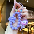Detalle de llavero de piruleta con cuentas moradas, lazo y cuentas de letras - Estilo Piruleta / Morado