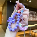 Makro-Detail des lila Perlen-Schlüsselanhängers mit Donut-Anhänger und Schleife - Lila Leuchtend Donut