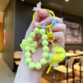 Detalle del llavero de piruleta amarilla con dijes de cuentas y esfera líquida de estrellas - Estilo Piruleta / Amarillo