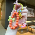 Detail of donut keychain with orange faux pearls and glitter sand pendant on a bag - Orange Luminous Snowflake Donut