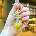 Detail of a yellow transparent resin strawberry keychain with a gold lobster clasp - Gold Hardware Electroplated Strawberry / Aurora Yellow