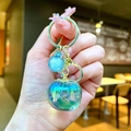 Detailed close-up of iridescent apple keychain with gold hardware and starry ball - Gold Hardware Green Electroplated Persimmon