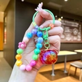 Dettaglio del portachiavi con perline arcobaleno, ciondolo a forma di frutto e lettere colorate - Perline Multicolore (Rosso)