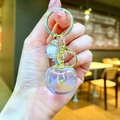 Iridescent apple keychain with gold metal ring and bubble bead detail shown in hand - Gold Hardware White Electroplated Persimmon