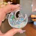 Detail of moon-shaped rabbit keychain with liquid glitter and golden metal clasp - White Luminous Rabbit