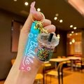 Close-up of cute milk tea cup keychain with liquid stars, gradient strap and gold lobster clasp - Black Luminous Bubble Bead Milk Tea Cup