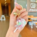 Lollipop shaker keychain with pink macarons, glitters, and a golden bell charm - White Snowflake Lollipop