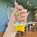 Star-shaped quicksand keychain with yellow liquid and golden bell on hand - Yellow Colorful Bead Pentagram