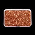 Close-up of rose gold irregular crushed stones in a transparent plastic box for nail art DIY - Tan