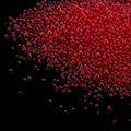 Macro shot of vibrant red translucent iridescent glass bubble beads on black background - Red