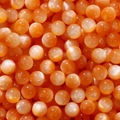 Macro shot of orange cat eye resin beads with silky luster for DIY jewelry making - Orange