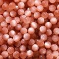 Macro detail of round light pink resin beads with cat-eye effect for jewelry making - Red Brown