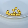 Dettaglio di perle tonde dorate con texture metallica sabbiata per la creazione di gioielli - Oro