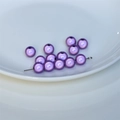 Macro di perline viola perlescenti per gioielli fai-da-te in un piatto di ceramica bianca - Viola Chiaro